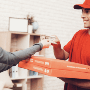 DoorDash delivery driver holding food orders near a busy restaurant.
